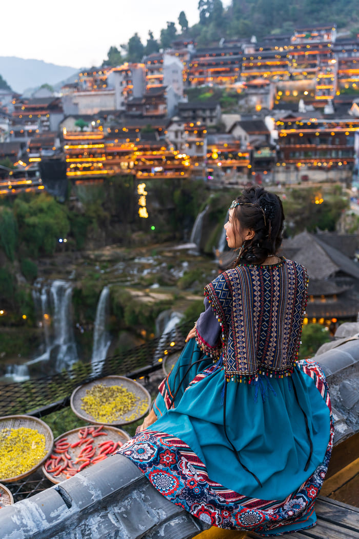 Viajes organizados a China por la ciudad Lijiang mujer mirando sobre un tejado